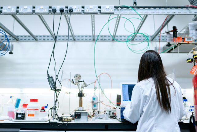 a woman works in a science lab wearing a white lab coat