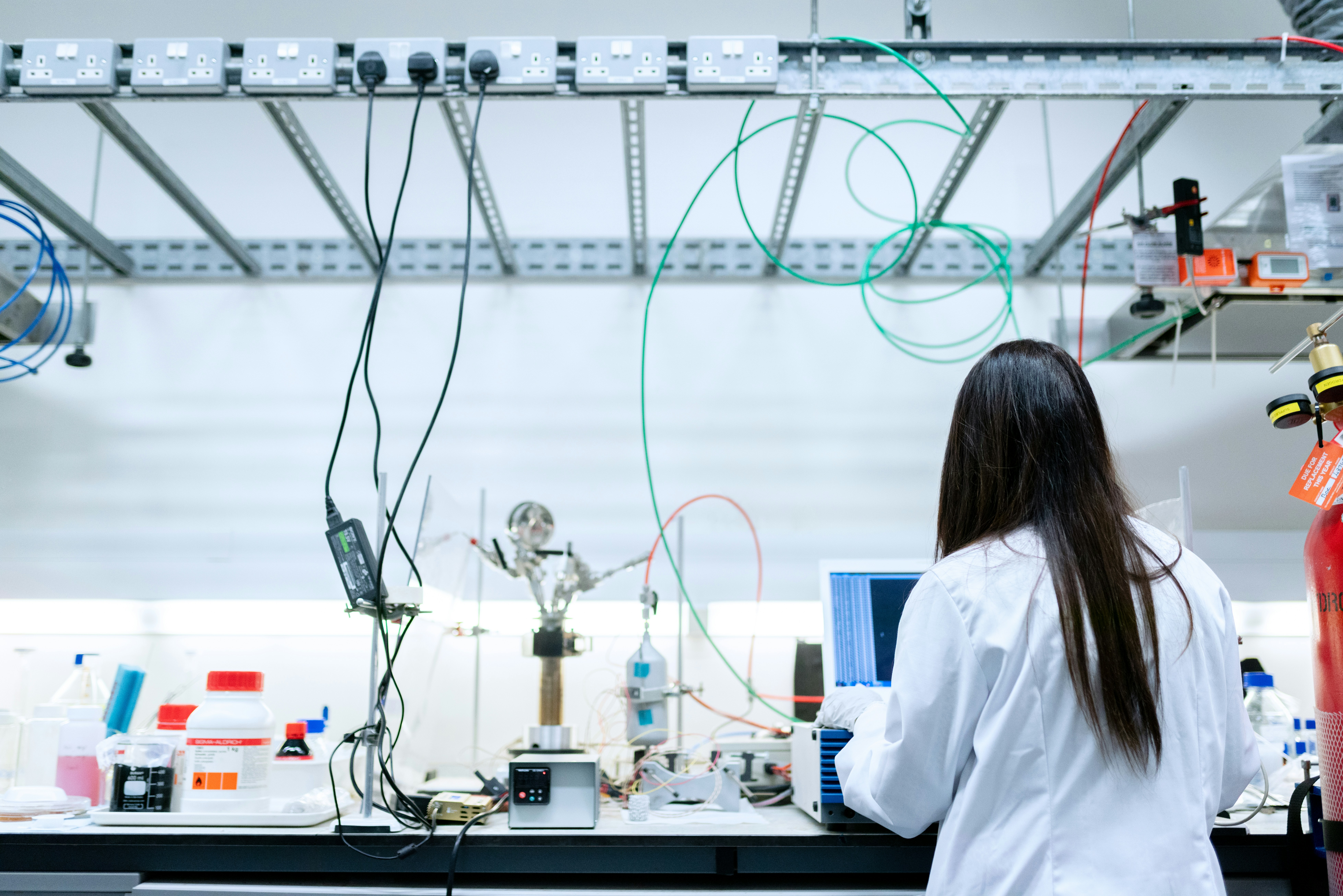 a woman works in a science lab wearing a white lab coat